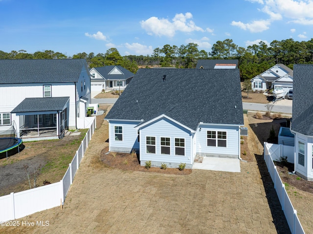 back of house with a shingled roof, a sunroom, a fenced backyard, a residential view, and a patio area