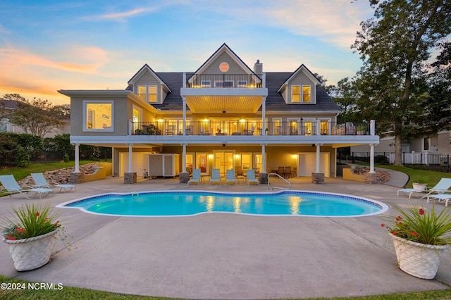 pool at dusk with a patio area