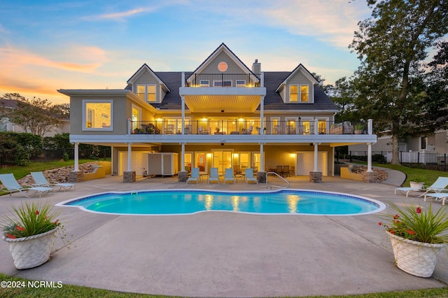 1324 Harbour Watch SW, Calabash, NC 28467 - back of property at dusk featuring a balcony, a patio area, fence, and an outdoor pool