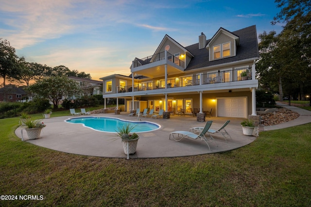 1324 Harbour Watch SW, Calabash, NC 28467 - back of house at dusk with a balcony, a patio area, an outdoor pool, a garage, and a chimney