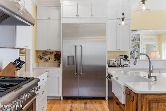 1324 Harbour Watch SW, Calabash, NC 28467 - kitchen featuring premium appliances, under cabinet range hood, a sink, light countertops, and white cabinetry