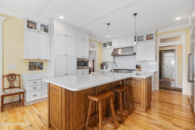 1324 Harbour Watch SW, Calabash, NC 28467 - kitchen with stainless steel microwave, wall chimney exhaust hood, light wood-style floors, a spacious island, and light countertops
