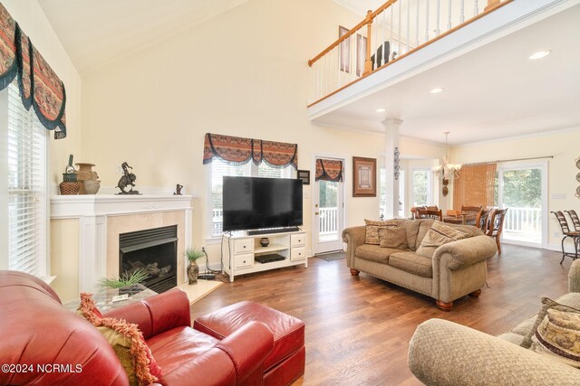 living room with a notable chandelier, hardwood / wood-style floors, a premium fireplace, and high vaulted ceiling