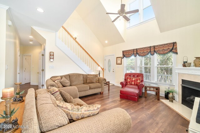 living room with ceiling fan, a premium fireplace, dark hardwood / wood-style flooring, and a high ceiling