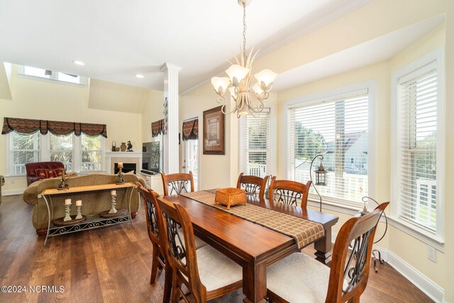 dining space with ornate columns, ornamental molding, a notable chandelier, and dark hardwood / wood-style flooring