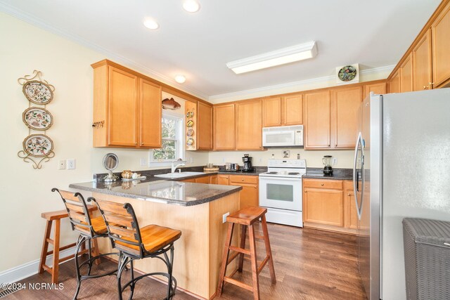 kitchen featuring dark wood-type flooring, white appliances, kitchen peninsula, a breakfast bar area, and ornamental molding