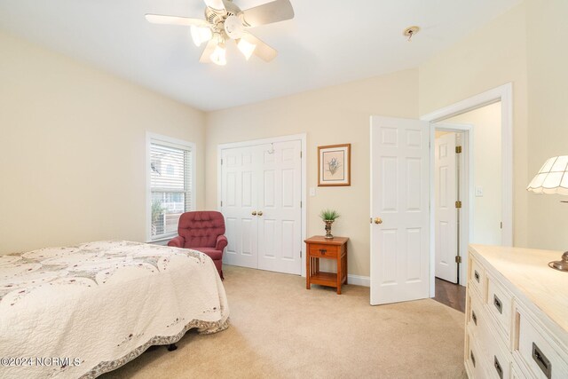 bedroom with ceiling fan, light colored carpet, and a closet