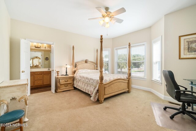 bedroom with ceiling fan, light colored carpet, and ensuite bath