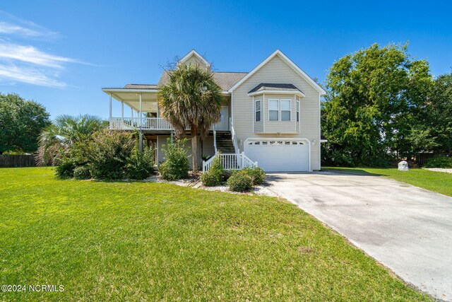 view of front of house featuring covered porch, a front yard, and a garage