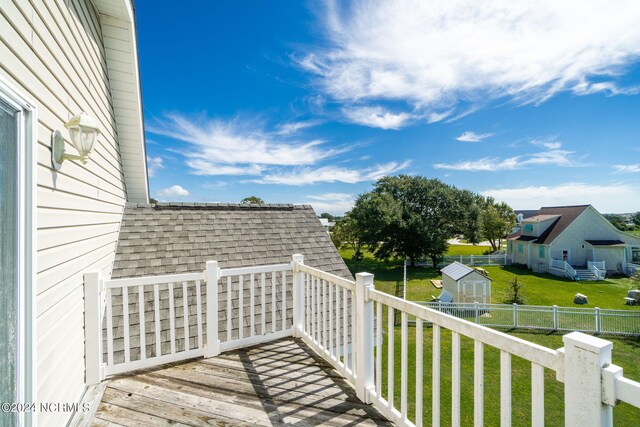 deck with a storage shed and a lawn