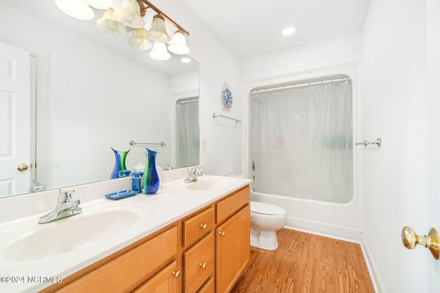 full bathroom with shower / tub combo with curtain, hardwood / wood-style floors, vanity, and toilet