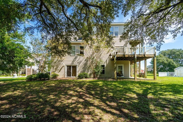 back of property featuring a lawn and a deck