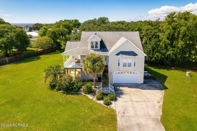 view of front of home with covered porch, a front yard, and a garage