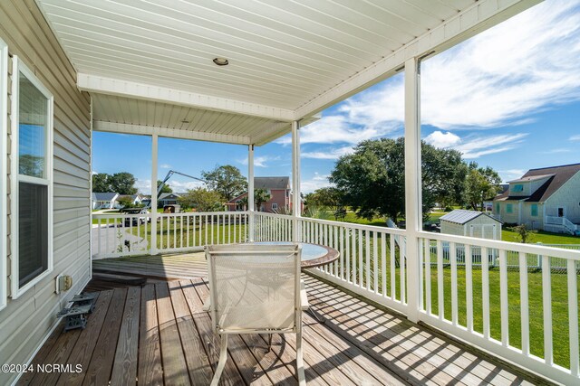 wooden terrace with a yard and a storage unit