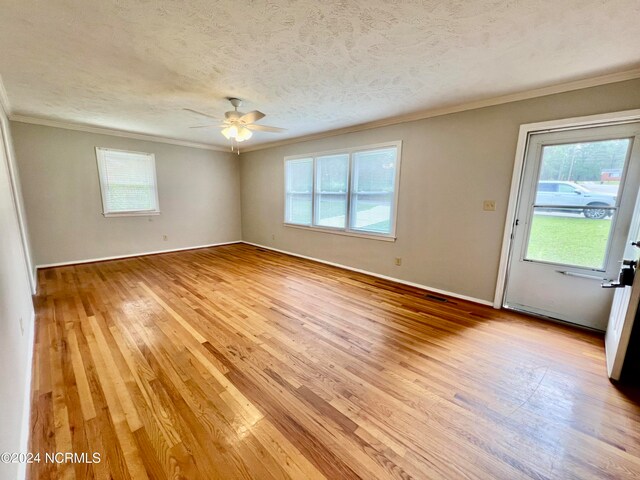 empty room featuring a textured ceiling, ceiling fan, wood-type flooring, and ornamental molding