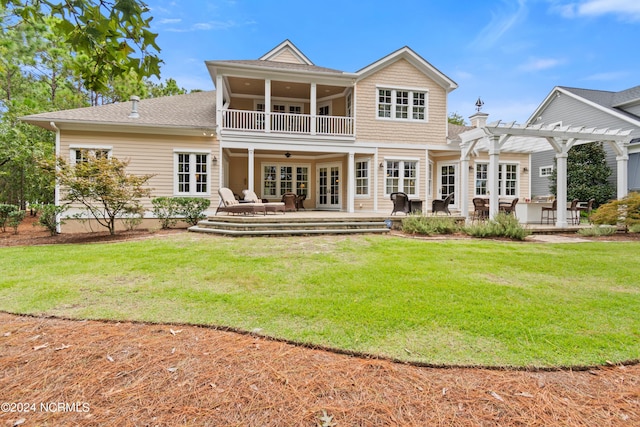 rear view of house with ceiling fan, a balcony, a yard, french doors, and a pergola