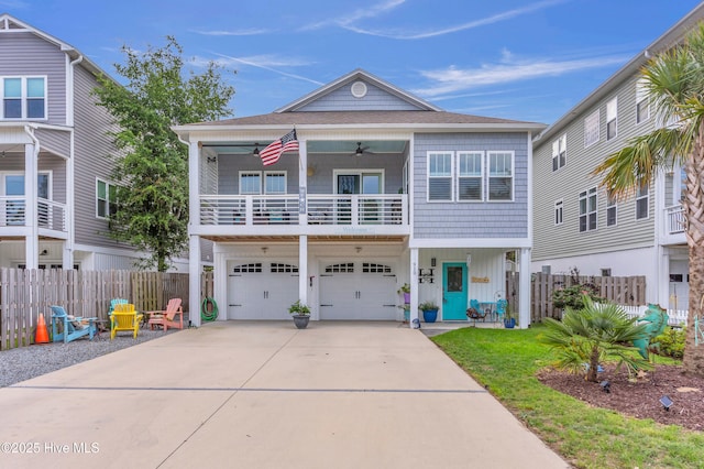 910 Old Dow Rd, Carolina Beach, NC 28428 - coastal home featuring a balcony, a garage, concrete driveway, board and batten siding, and a ceiling fan