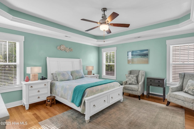 910 Old Dow Rd, Carolina Beach, NC 28428 - bedroom with a tray ceiling, multiple windows, wood finished floors, baseboards, and crown molding