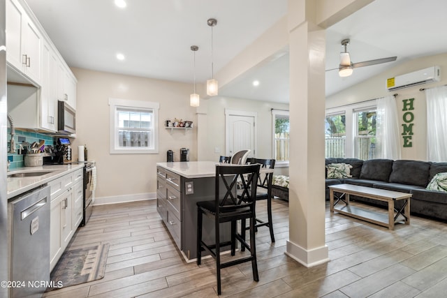 kitchen featuring stainless steel appliances, a kitchen island, a kitchen breakfast bar, pendant lighting, and white cabinets