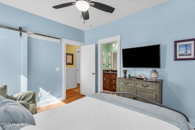 910 Old Dow Rd, Carolina Beach, NC 28428 - bedroom with wood finished floors, a barn door, a sink, a ceiling fan, and baseboards