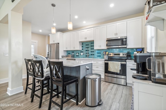 910 Old Dow Rd, Carolina Beach, NC 28428 - kitchen with stainless steel appliances, a kitchen island, a kitchen breakfast bar, white cabinets, and decorative backsplash