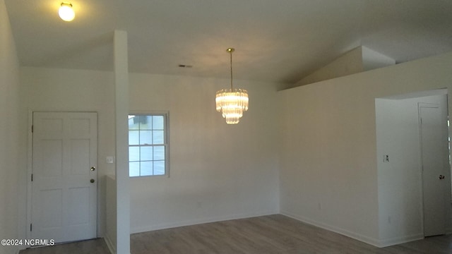 spare room with a notable chandelier, lofted ceiling, and hardwood / wood-style floors