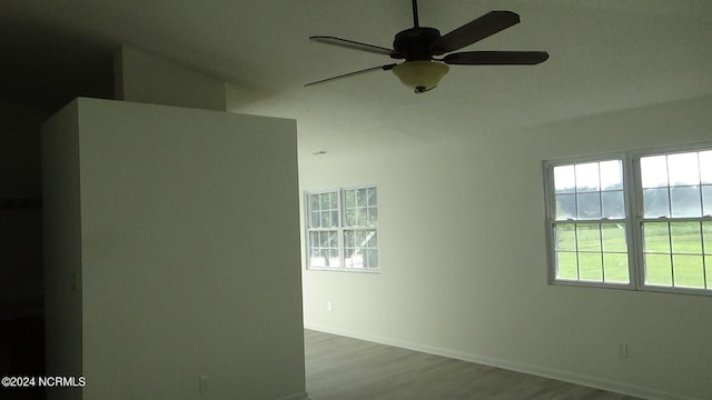 empty room with hardwood / wood-style floors, ceiling fan, and a healthy amount of sunlight