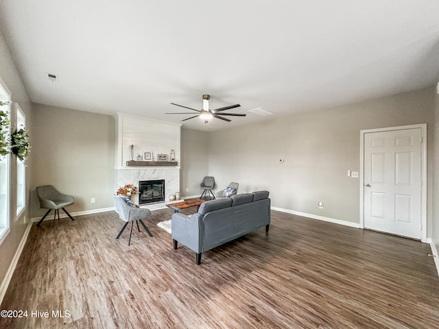 living room with a high end fireplace, wood-type flooring, and ceiling fan