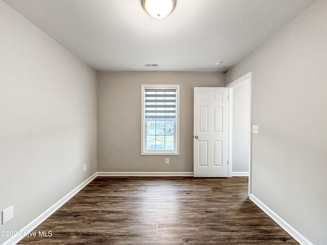 unfurnished room with dark wood-type flooring