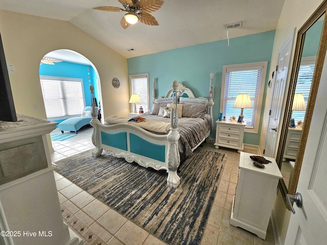 tiled bedroom featuring ceiling fan, vaulted ceiling, and multiple windows