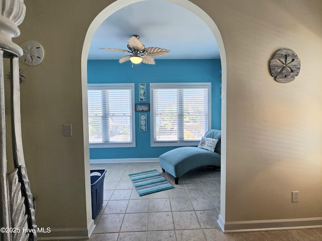 living area with light tile patterned floors and ceiling fan