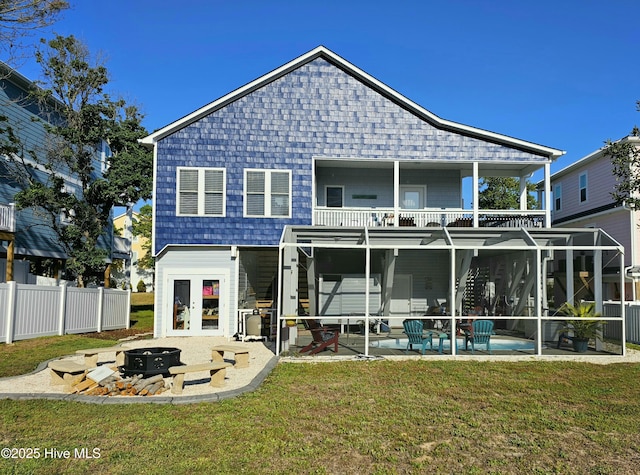 back of house featuring a patio, glass enclosure, a balcony, an outdoor fire pit, and a yard