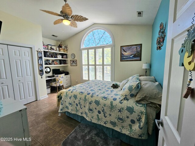 bedroom featuring vaulted ceiling, ceiling fan, dark tile patterned flooring, a closet, and built in desk