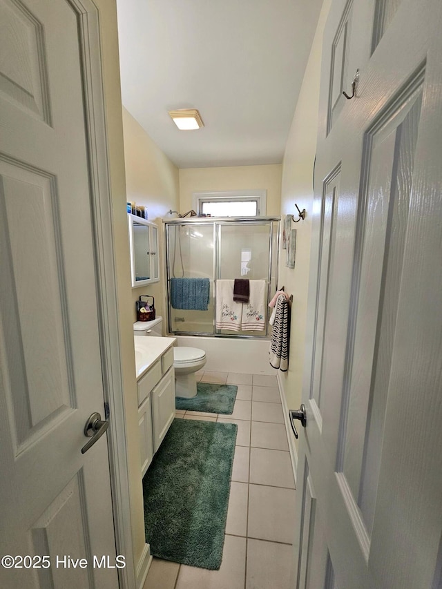 full bathroom featuring vanity, shower / bath combination with glass door, tile patterned floors, and toilet