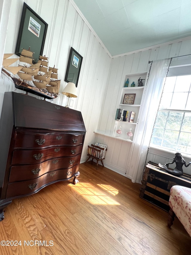 living area featuring light hardwood / wood-style floors, crown molding, and built in features