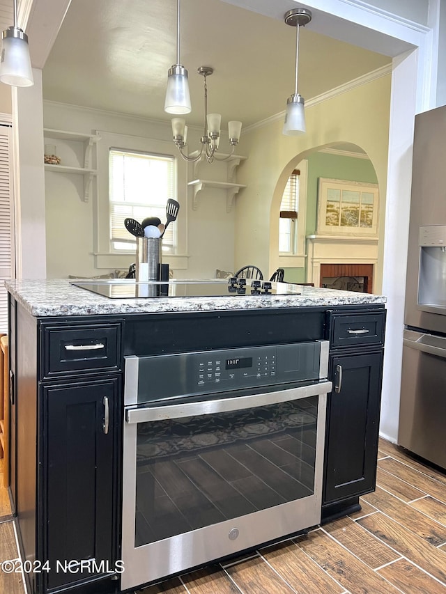 kitchen featuring ornamental molding, stainless steel appliances, pendant lighting, and hardwood / wood-style floors