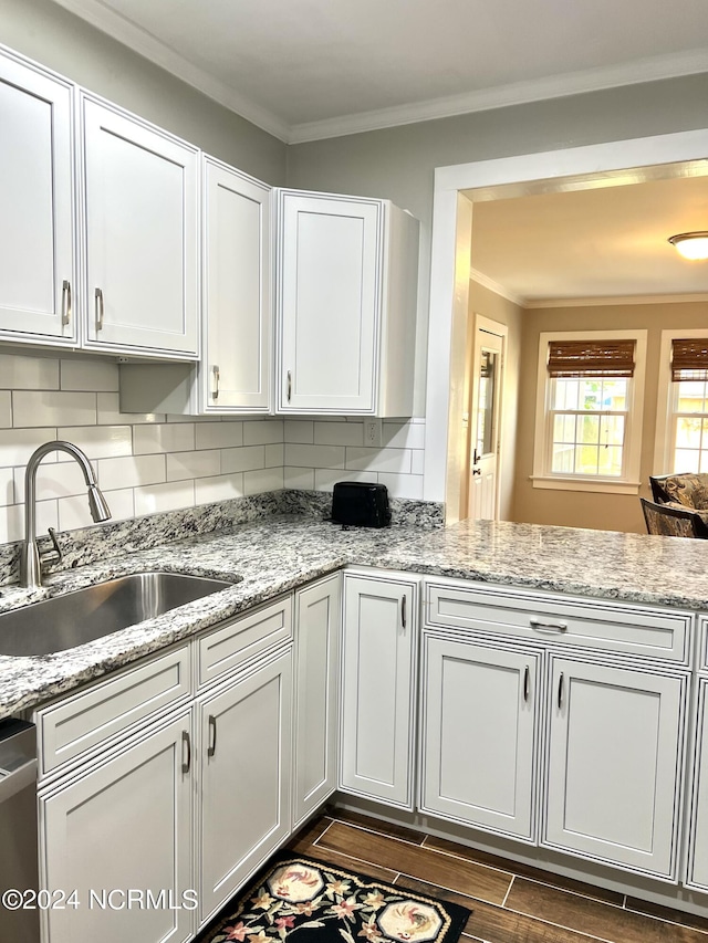 kitchen featuring dark wood-type flooring, white cabinets, crown molding, stainless steel dishwasher, and sink