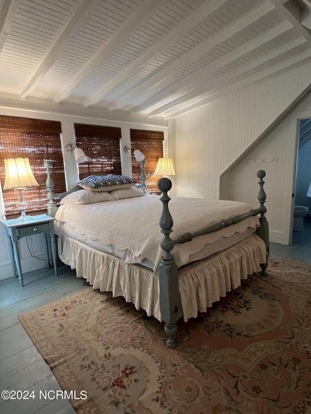 bedroom featuring wood-type flooring and beamed ceiling