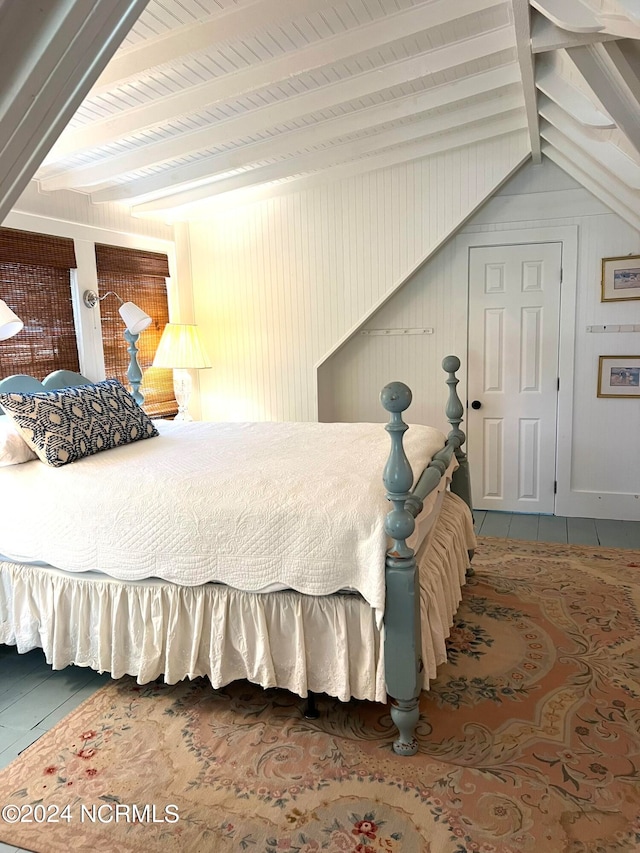 bedroom with wooden walls and vaulted ceiling with beams