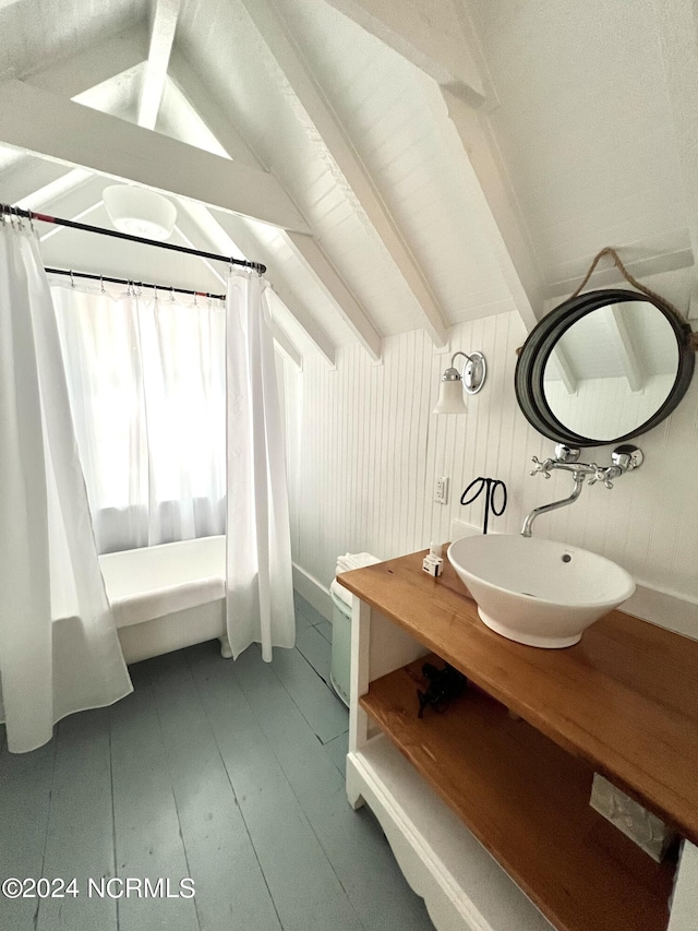 bathroom with vaulted ceiling with beams, vanity, wood walls, wood-type flooring, and a shower with shower curtain