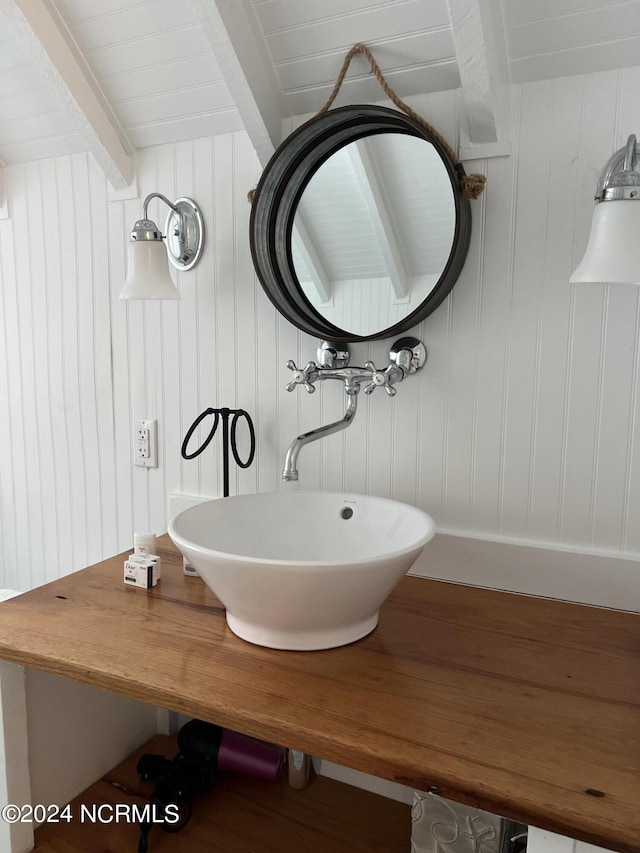 bathroom featuring hardwood / wood-style floors, wood walls, and sink