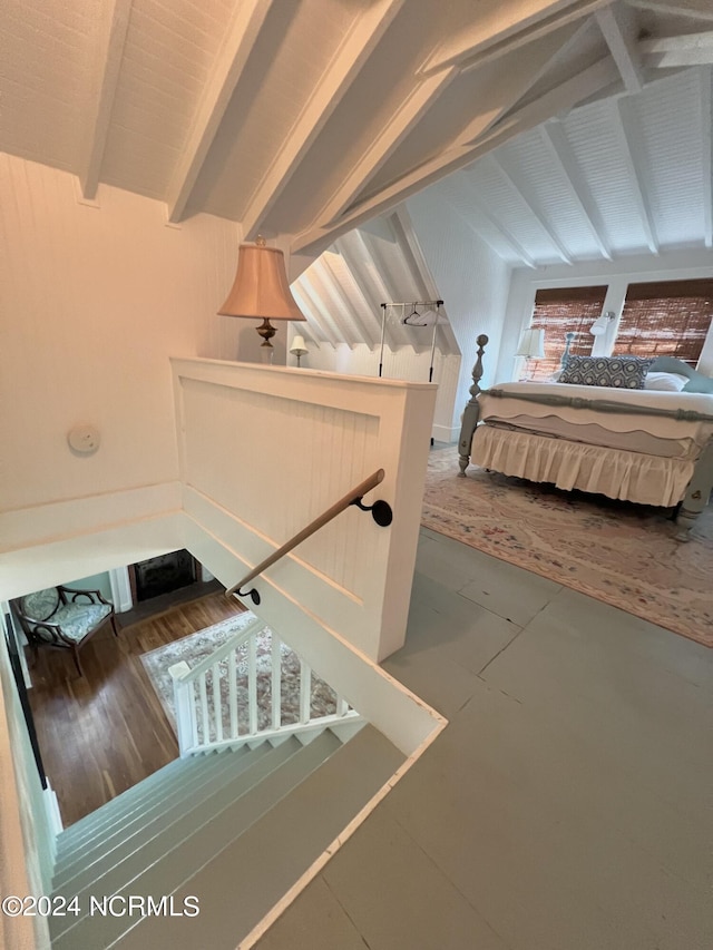 stairway with lofted ceiling with beams and hardwood / wood-style flooring