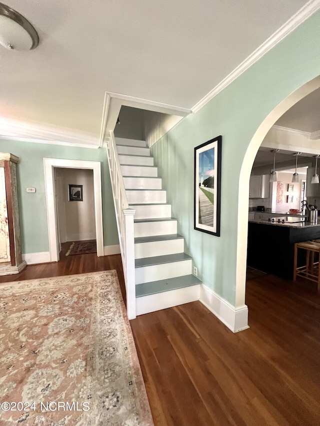 staircase with wood-type flooring and ornamental molding