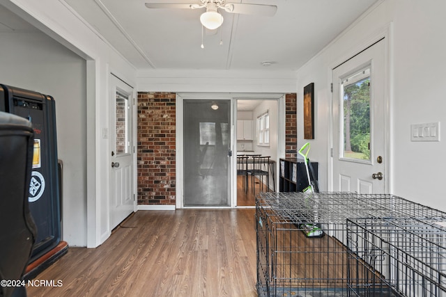 interior space with wood-type flooring, ceiling fan, brick wall, and crown molding