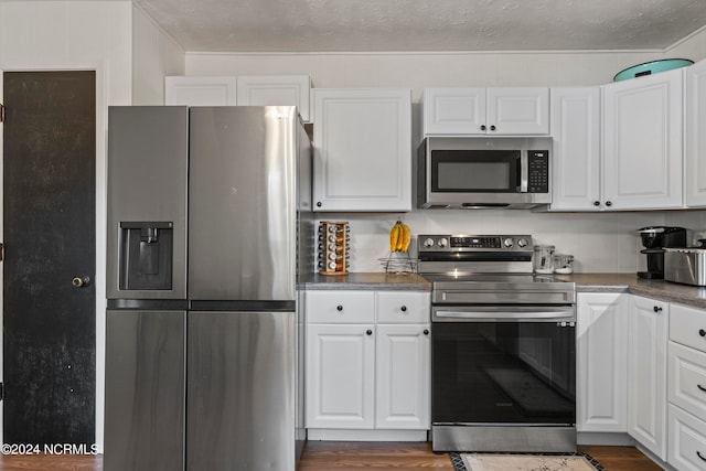 kitchen featuring a textured ceiling, appliances with stainless steel finishes, dark hardwood / wood-style flooring, and white cabinetry