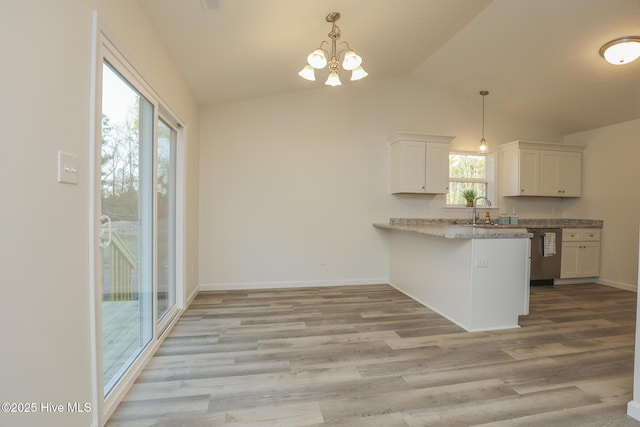 kitchen featuring lofted ceiling, light wood finished floors, white cabinetry, and stainless steel dishwasher