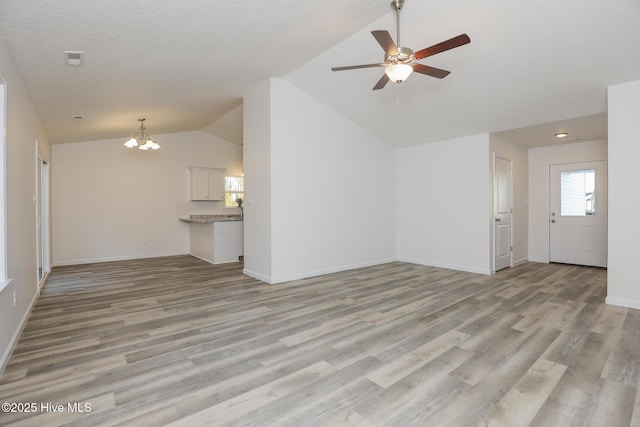 unfurnished living room with light wood finished floors, visible vents, baseboards, and vaulted ceiling