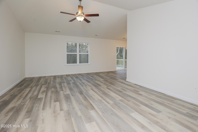 empty room featuring light wood-type flooring, vaulted ceiling, ceiling fan, and baseboards