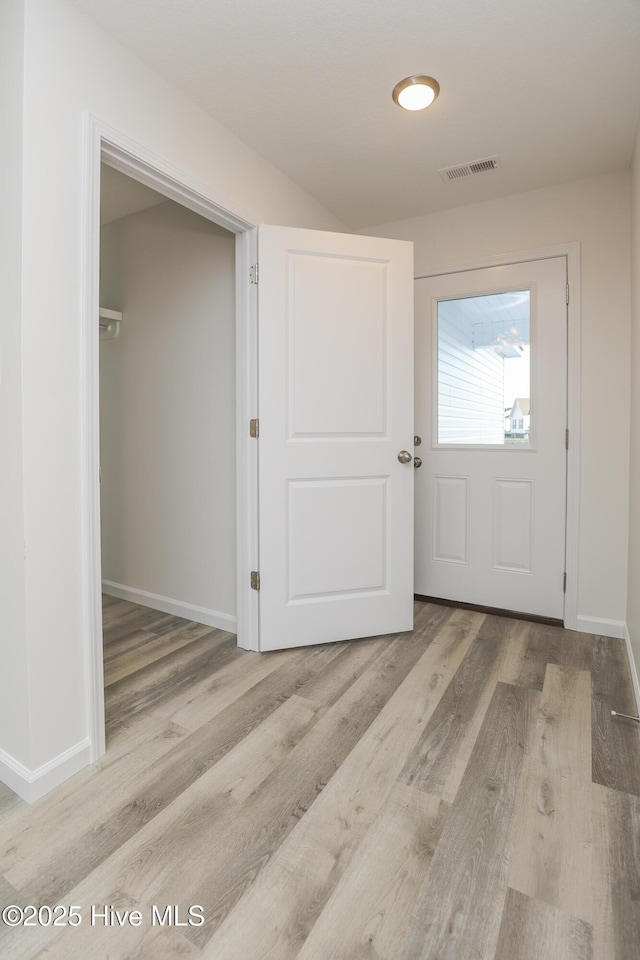 foyer entrance with baseboards, visible vents, and wood finished floors