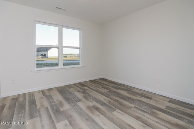 empty room featuring visible vents, baseboards, and wood finished floors